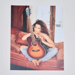 Person sitting with guitar on red couch.