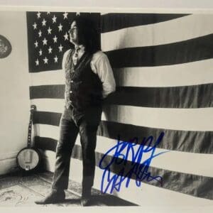 Man standing by American flag, signed photo.