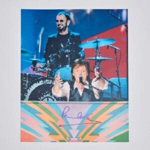 Musicians performing on colorful stage, autograph below.