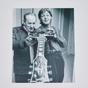 Two men holding a guitar together.