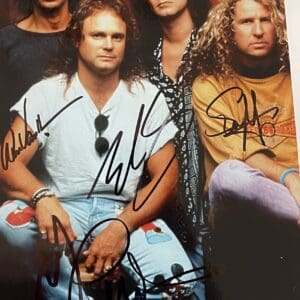 Four men posing with autographs on photo.