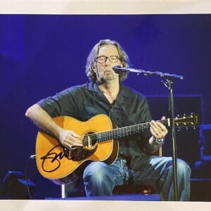 Musician playing acoustic guitar on stage.