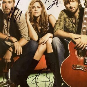 Three people with guitar, sitting together.