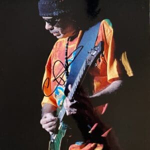 Guitarist performing in colorful shirt on stage.