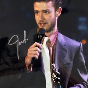 Man holding microphone and award, wearing suit.
