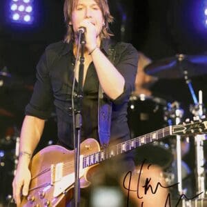 Musician performing on stage with guitar.
