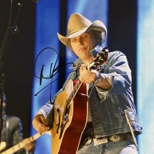 Cowboy hat musician playing acoustic guitar onstage.