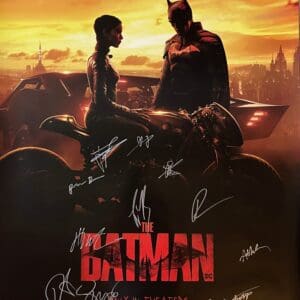Batman movie poster with autographs, sunset background.