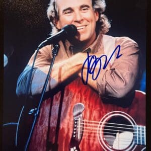 Man smiling with guitar, microphone, and signature.