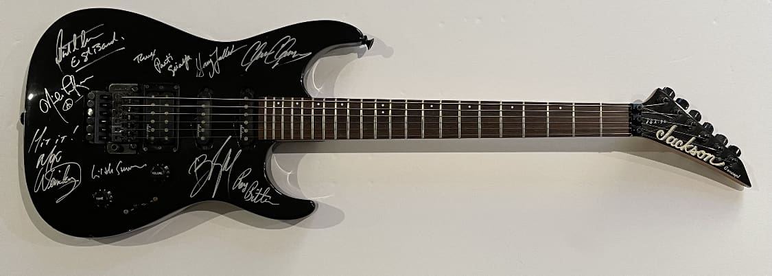 Black electric guitar with white signatures.