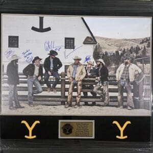 Cowboys posing by fence with autographs.