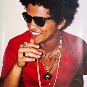 Man in red shirt wearing sunglasses, smiling.