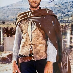 Cowboy in hat and poncho, holding gun.