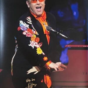 Musician playing piano with colorful floral jacket.