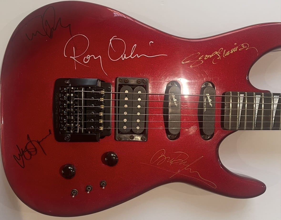 Red electric guitar with multiple signatures.
