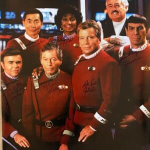 Starfleet crew in red uniforms, posing together.