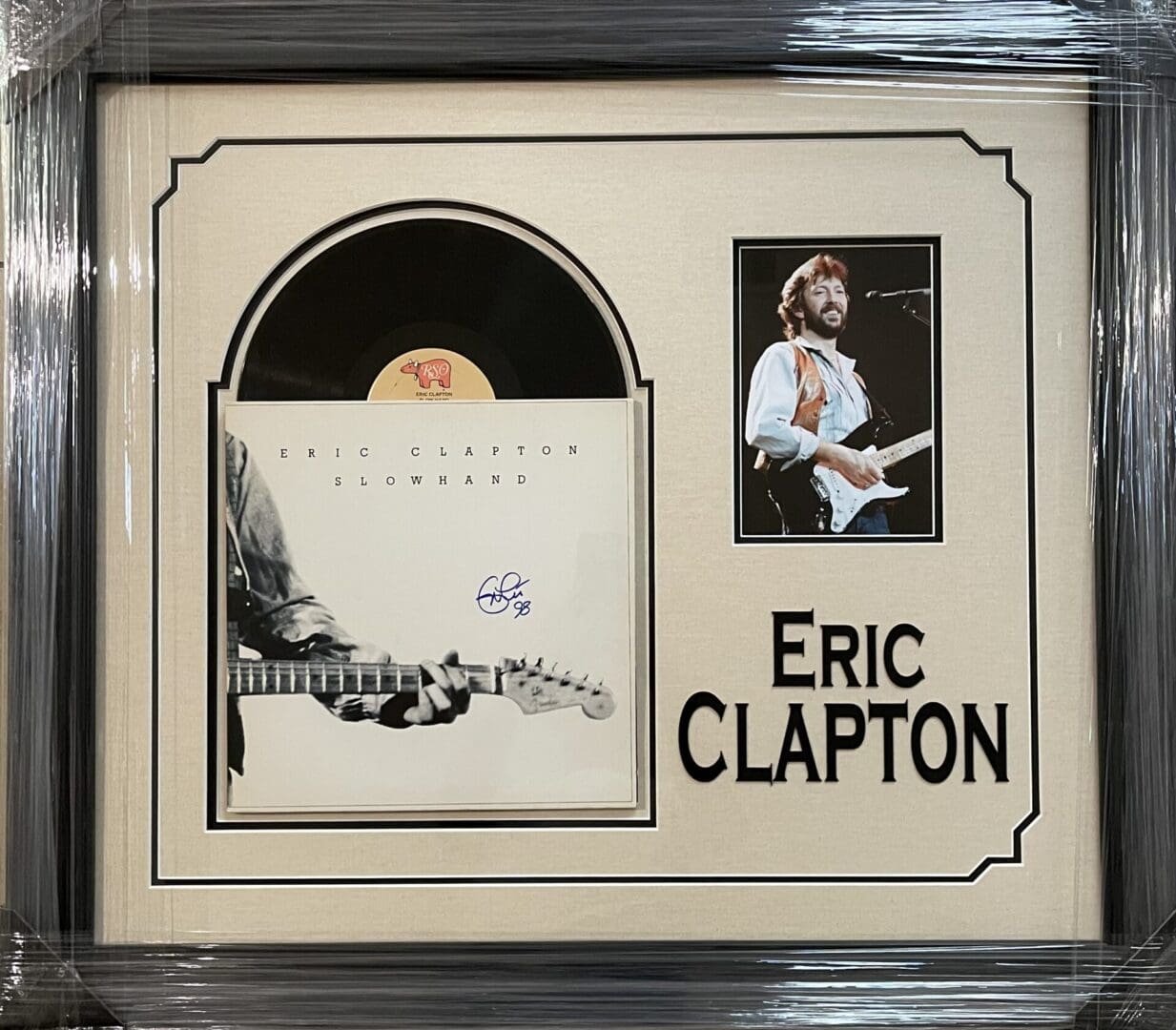 Framed Eric Clapton album and photograph display.