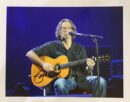 Musician playing acoustic guitar on stage.