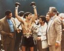 Boxer celebrating victory with supporters around.