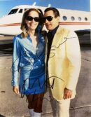 Couple in sunglasses posing by private jet.