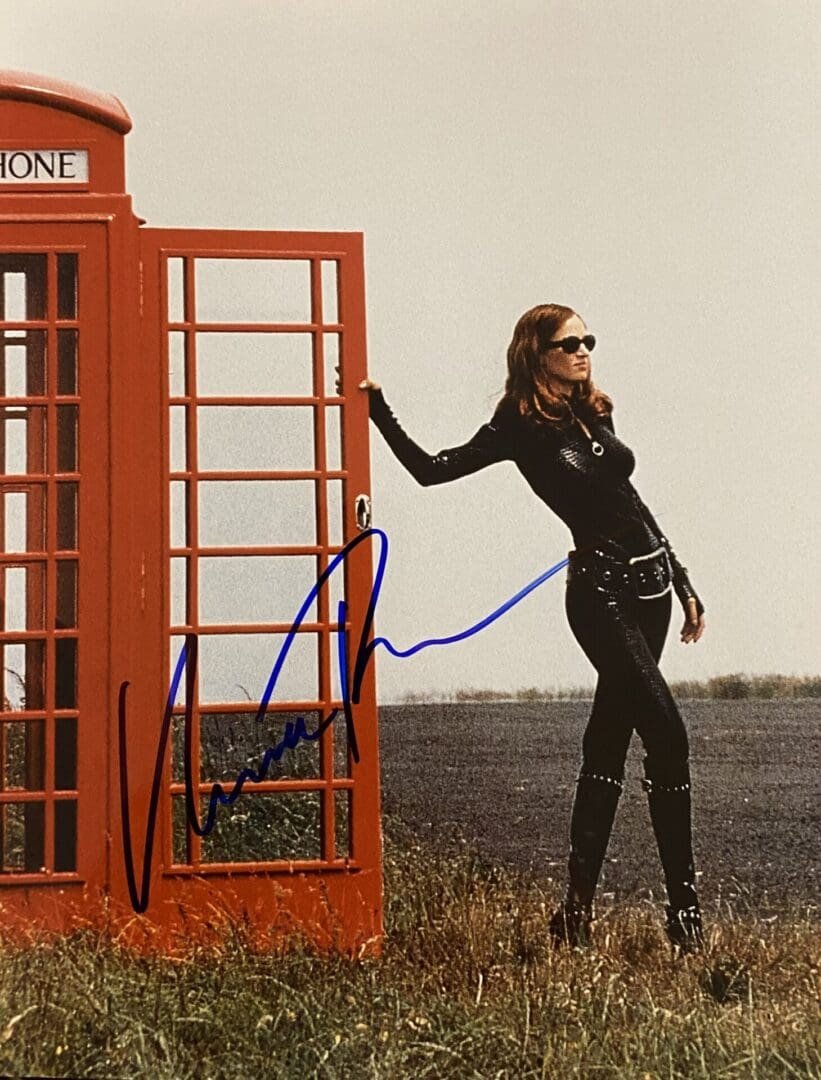Woman in black outfit by red phone booth.