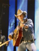 Cowboy hat musician playing acoustic guitar onstage.