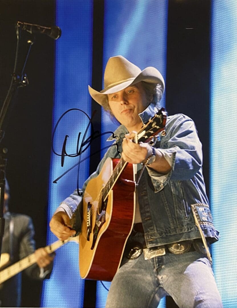 Cowboy hat musician playing acoustic guitar onstage.