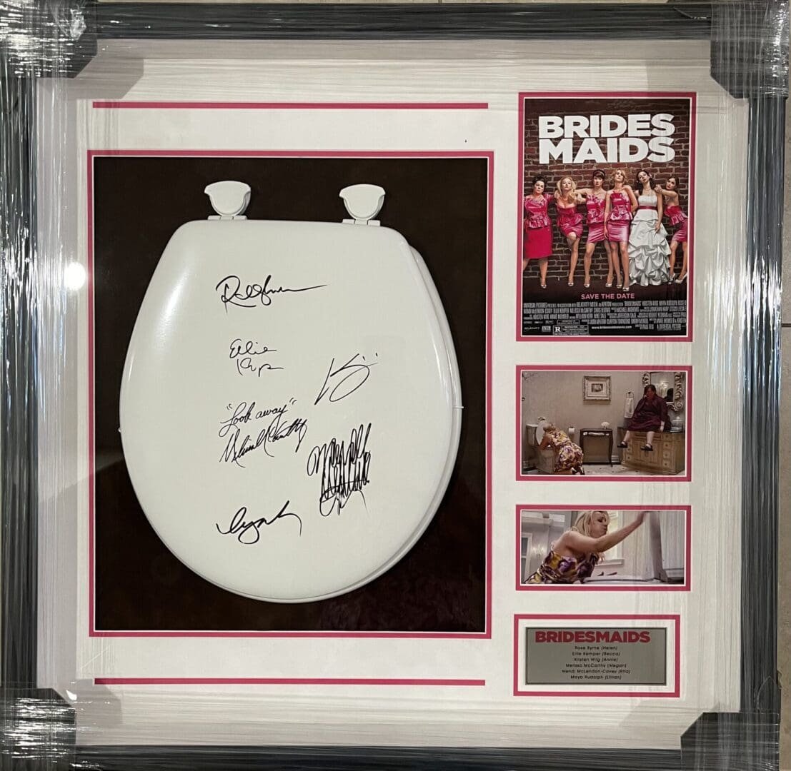 Framed autographed toilet seat with Bridesmaids poster.