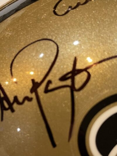 Gold helmet with black signature and logo.