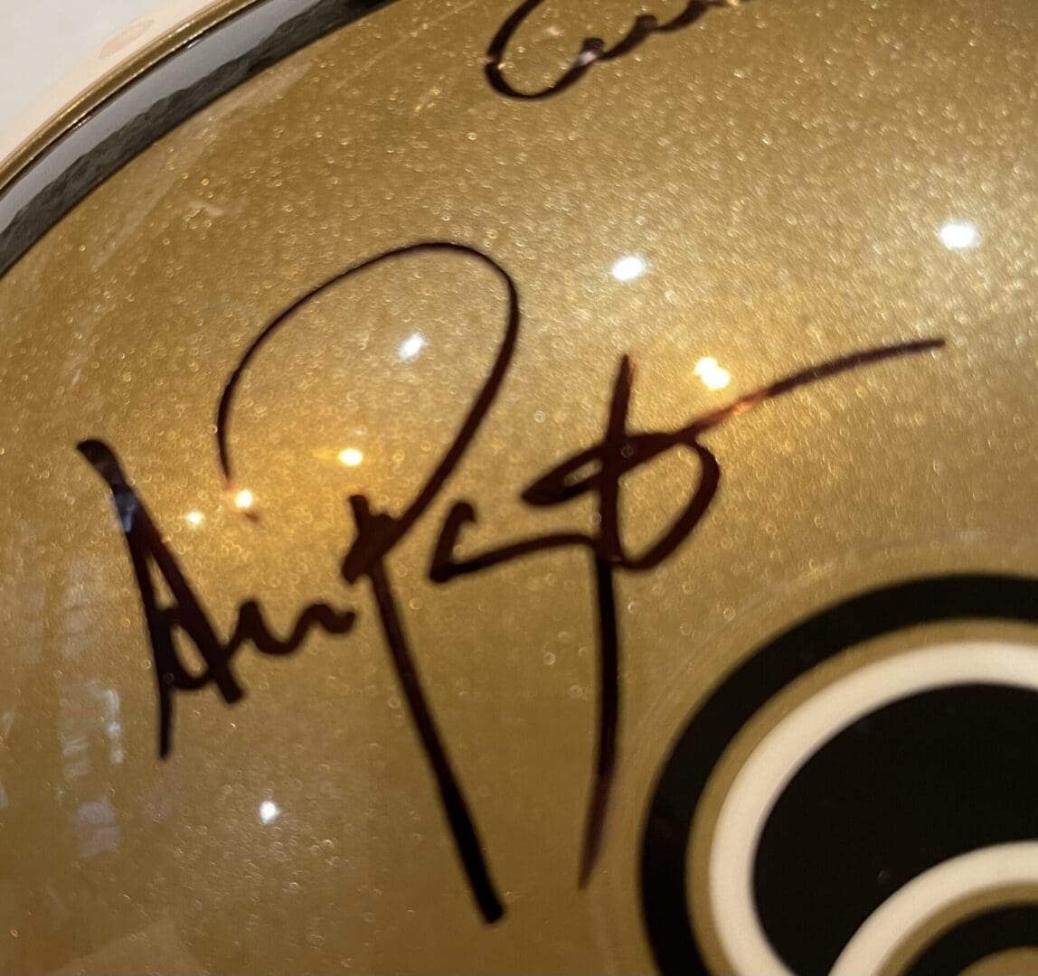 Gold helmet with black signature and logo.