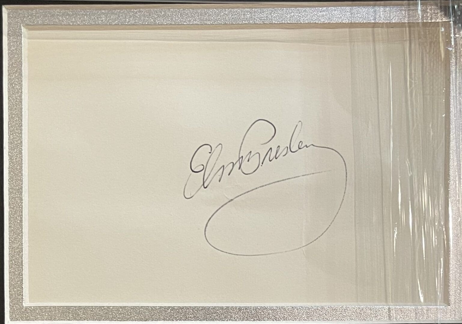 Signature on white paper in a frame.