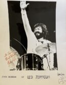 Drummer smiling and waving behind drum kit.