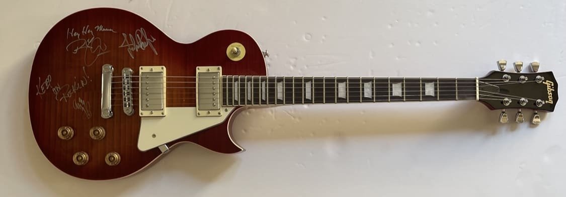 Red electric guitar with multiple signatures.