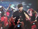 Rapper performing on stage with crowd cheering.