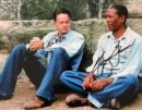 Two men sitting against a stone wall.