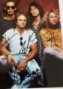Four men posing with autographs on photo.