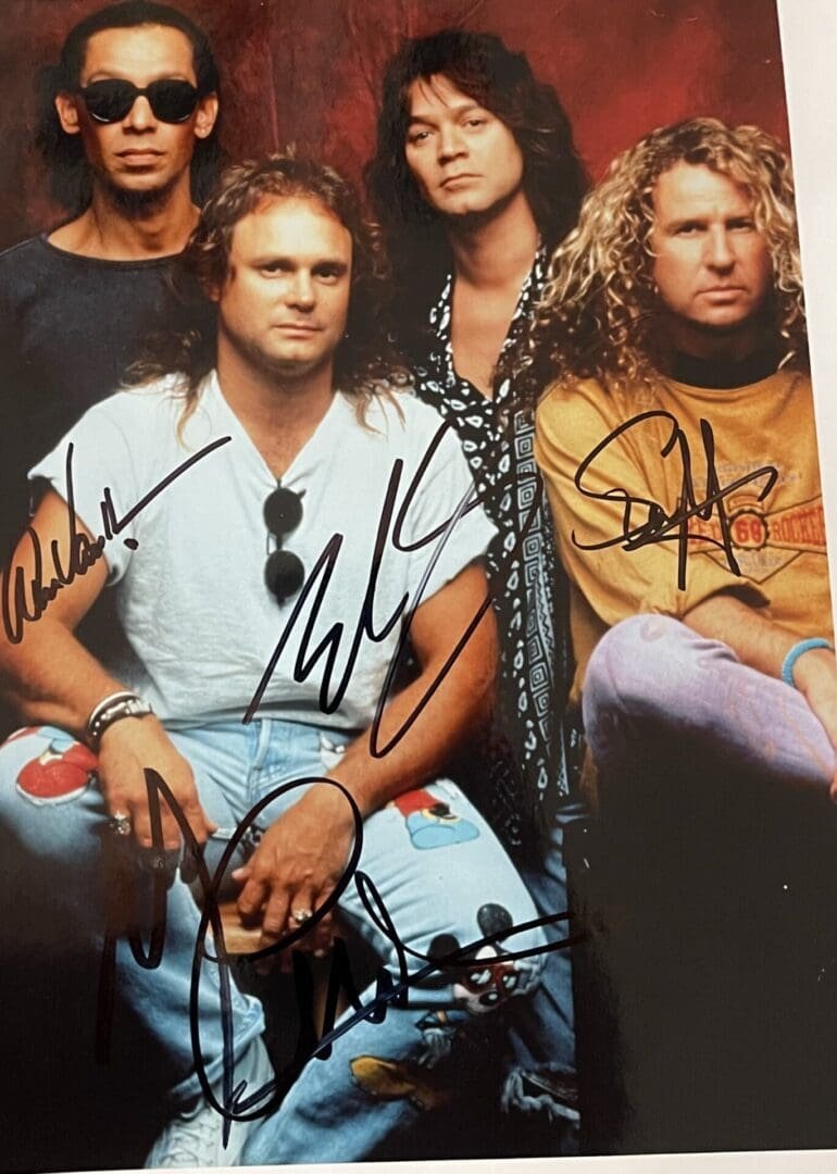 Four men posing with autographs on photo.