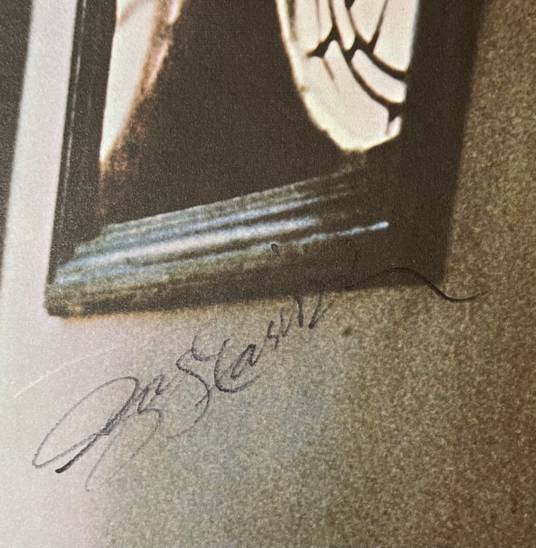 Close-up of a framed picture with signature.