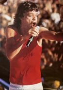 Singer performing energetically in red tank top.