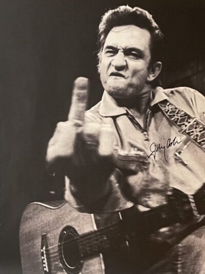 Musician with guitar making bold gesture.