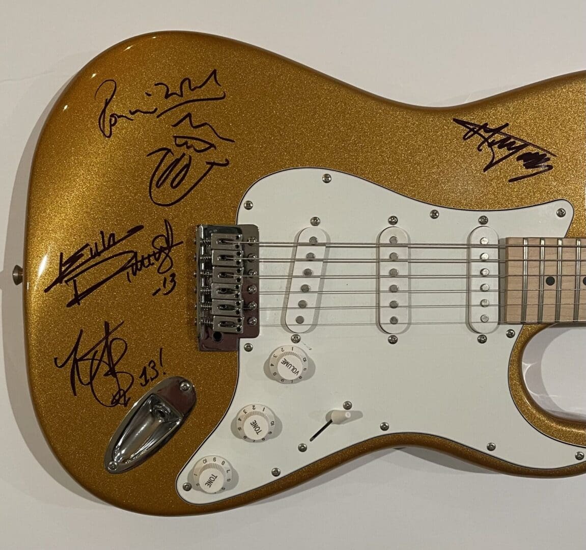 Gold electric guitar with multiple autographs.