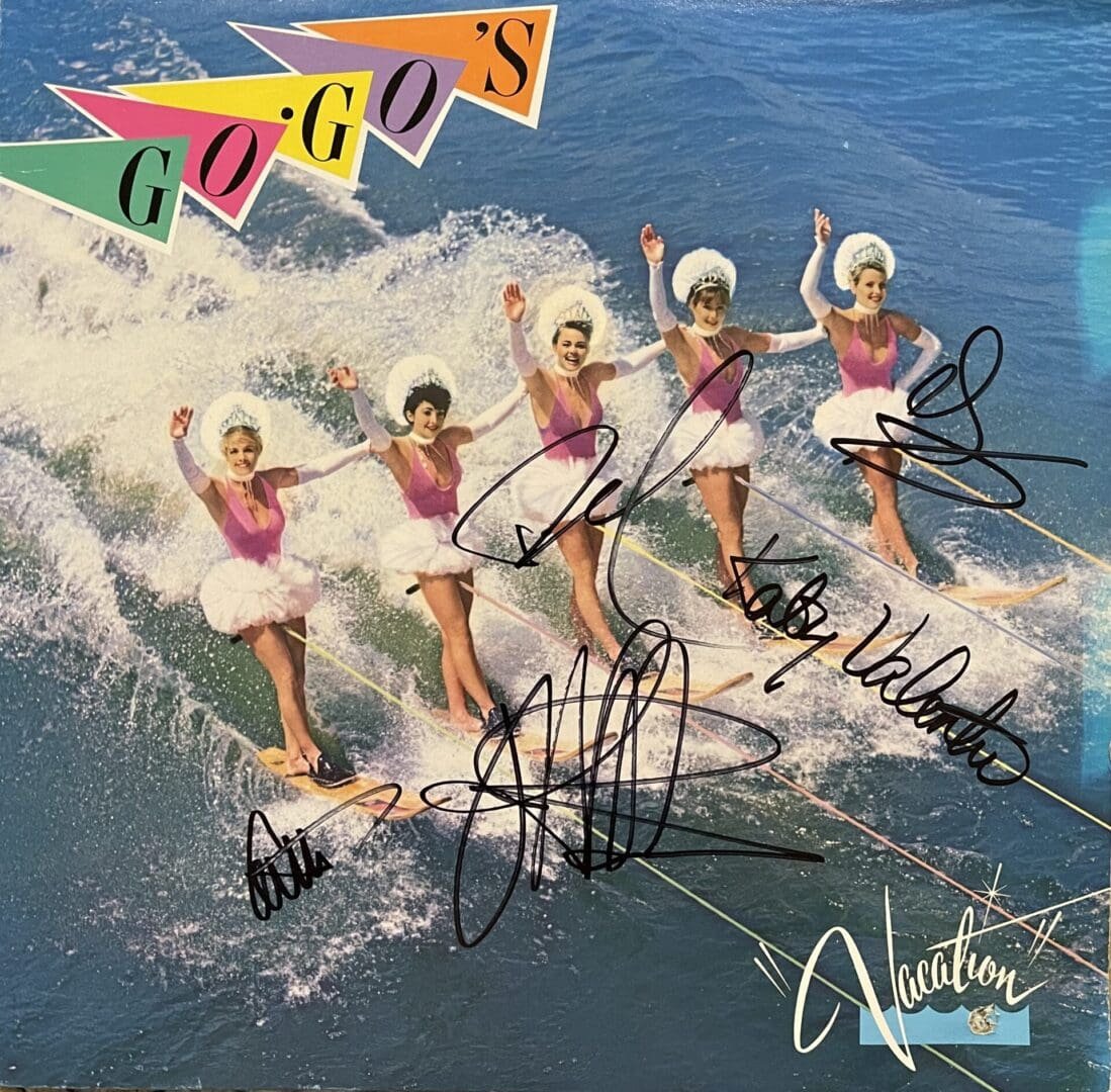 Water-skiing performers in pink outfits waving.