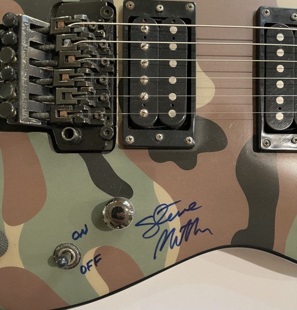 Camouflage guitar with signature and controls.