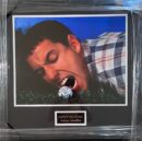 Man biting golf ball on grass.