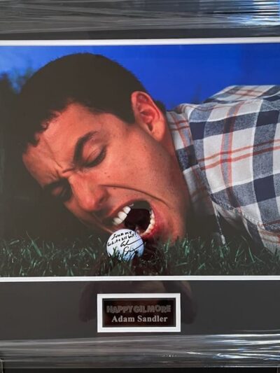 Man biting golf ball on grass.