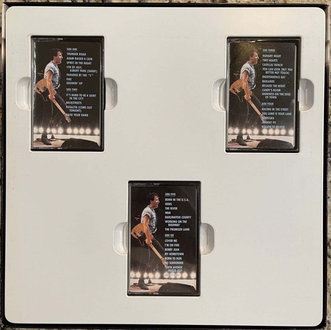 Three concert setlists in a display case.