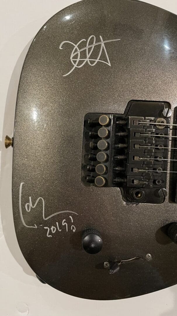 Signed electric guitar body with bridge visible.