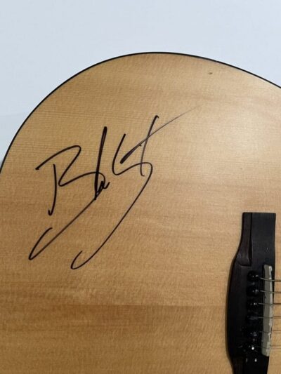 Acoustic guitar with signature on wooden body.