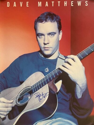 Musician playing acoustic guitar against red background.