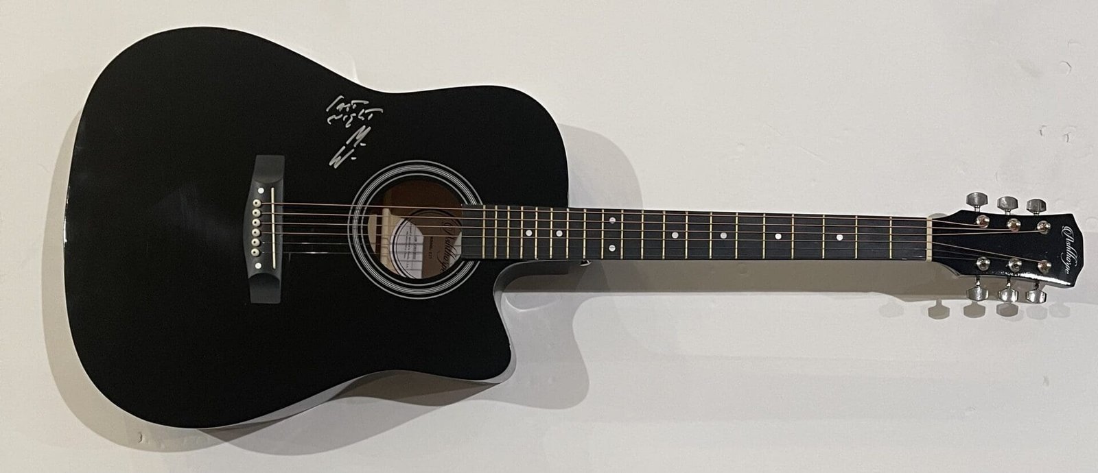 Black acoustic guitar with white signature.